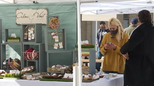 Customers browsing an art vendor at the Red Stick Farmers Market